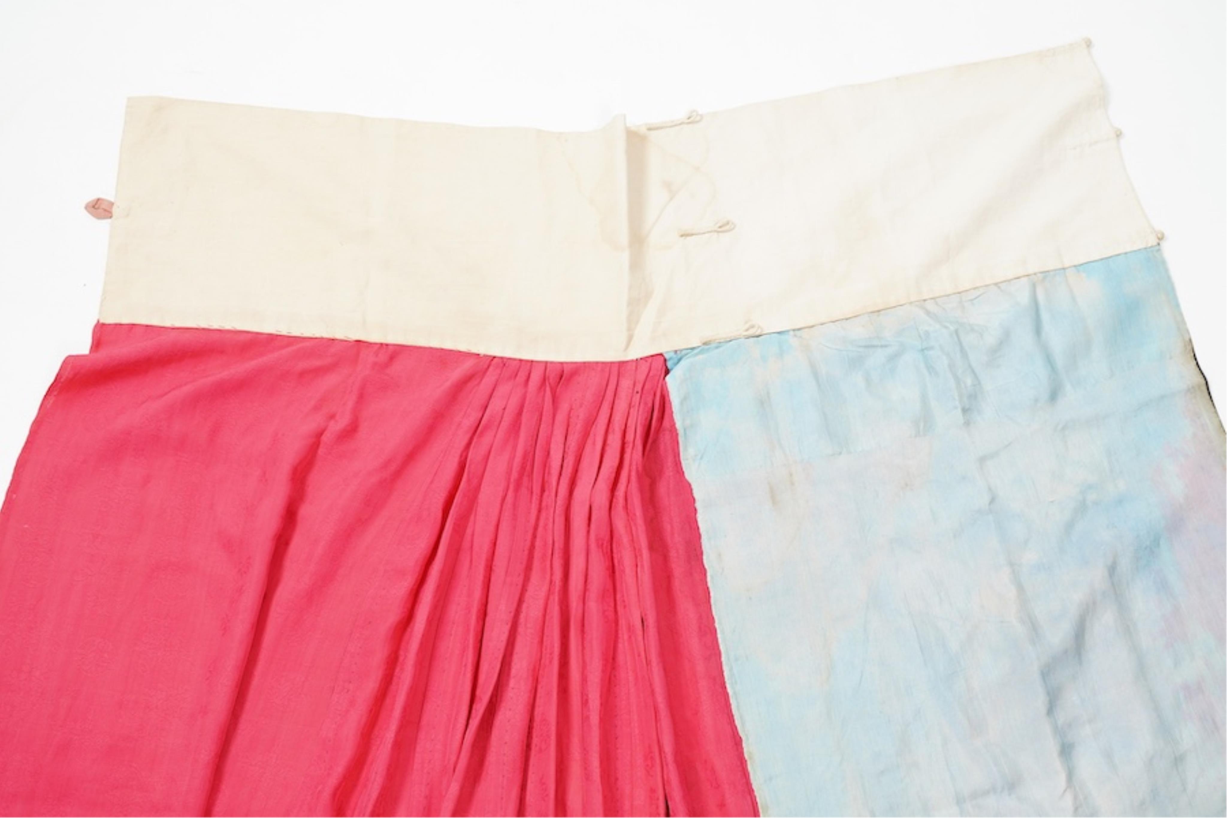 Two late 19th early 20th century Chinese wedding skirts. Made with pink silk damask, embroidered with large decorative silk floral and butterfly front panels bordered by blue embroidered black silk borders between pleats